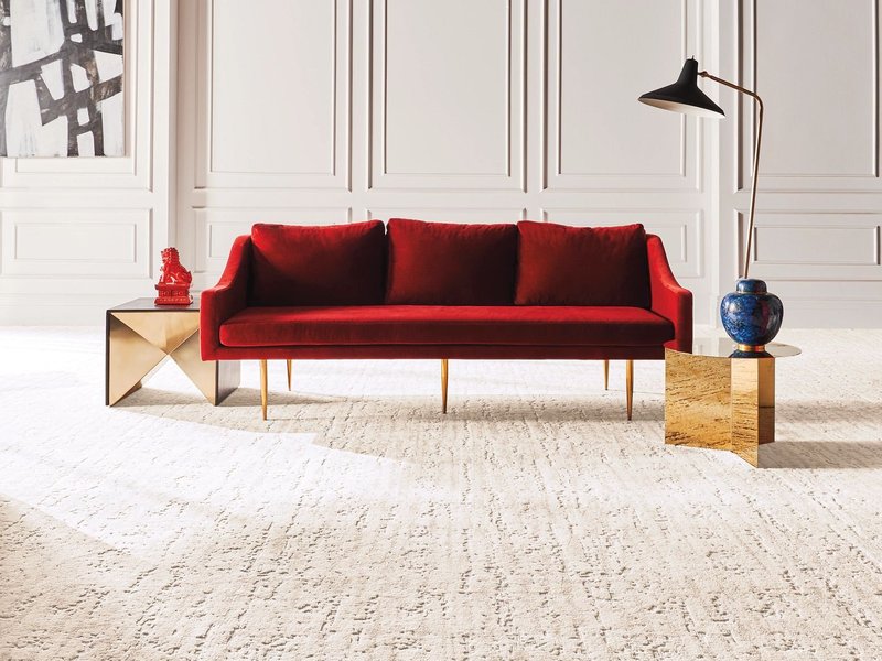 Bright living room with a red velvet couch and beige textured carpet from Carpet & Flooring By Denny Lee in Abingdon, MD